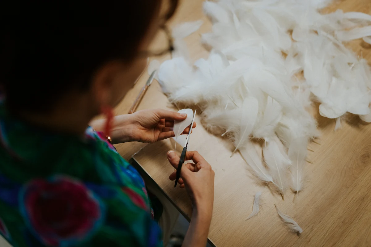 amandine-decoupe-les-plumes-oie-de-dos Amandine, plumassière, découpe ses plumes d'oie délicatement.
